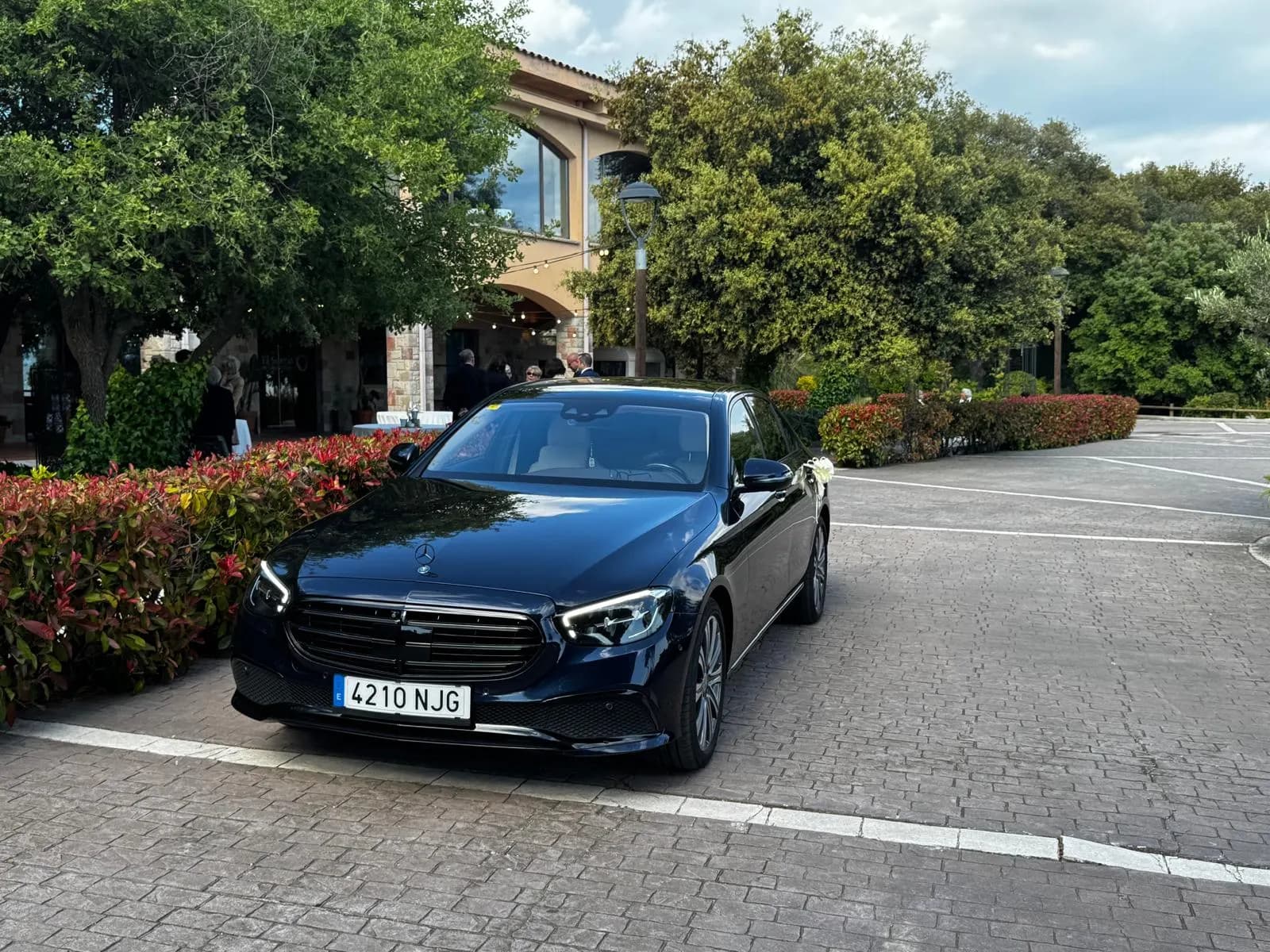 Mercedes E-Class wedding car with white ribbon and flowers at a Catalan masia venue